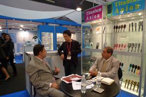 Visitors and an exhibitor discussing products around a table at the Italy exhibition booth